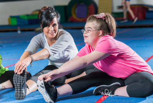 Trainerin mit Sportlerin mit Down-Syndrom wärmen sich